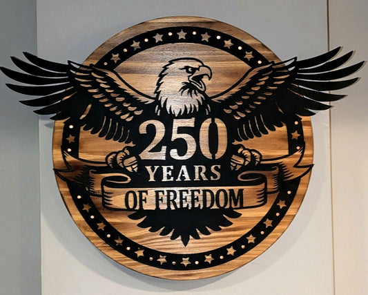 Eagle 250 Years of Freedom sign — matte black cut steel on a stained wood round, with copper nail accents