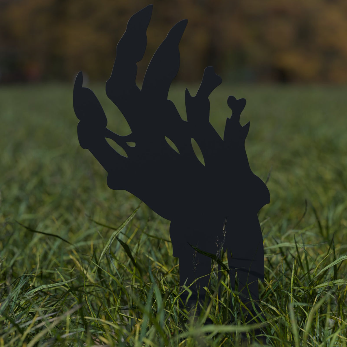 Close-up of a black steel zombie hand yard stake in the grass