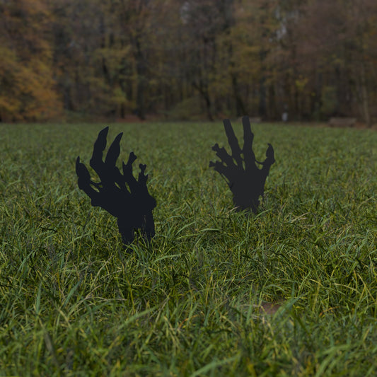 Two zombie hand silhouette yard stakes reaching up out of a lawn